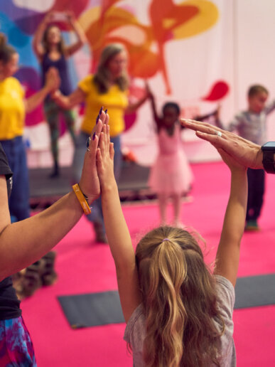 kid holding hands with her parents at a yoga event