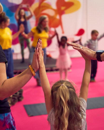 kid holding hands with her parents at a yoga event