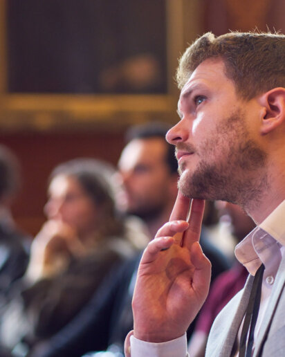 Candid moment for someone listening to a speaker on stage and deep in thought