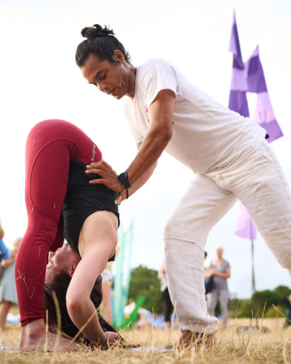 Yoga teacher adjusting his student