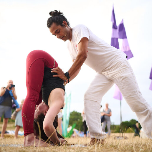 Yoga teacher adjusting his student
