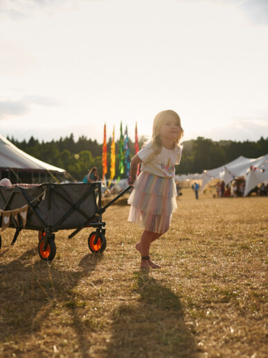 Kid pulling her toys during a sunset at a yoga festival
