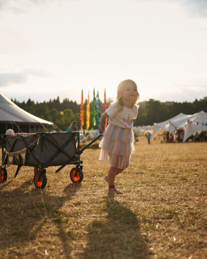 Kid pulling her toys during a sunset at a yoga festival
